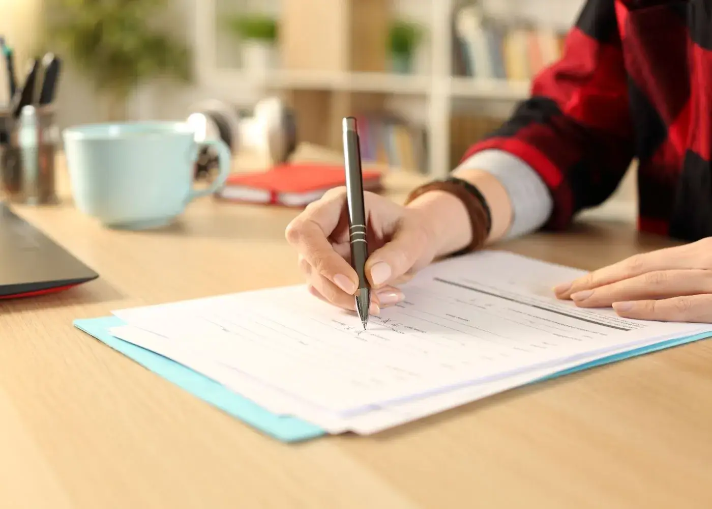 A person filling out an application form with a pen